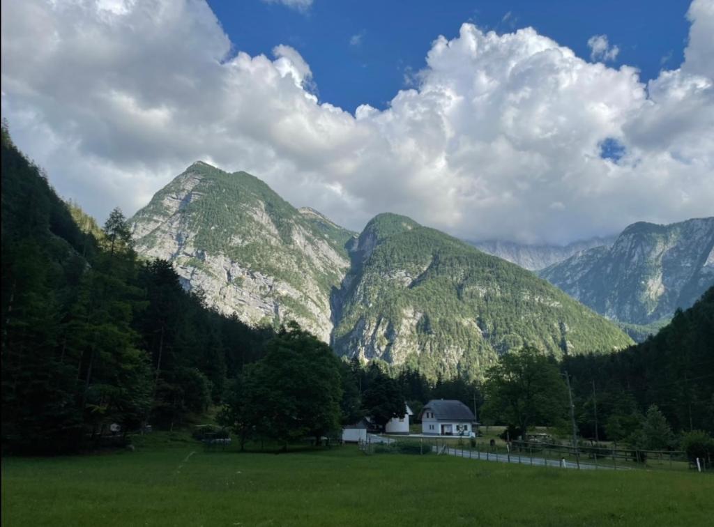 une maison dans un champ avec des montagnes en arrière-plan dans l'établissement Juliana Cottage, à Vallée de la Soča