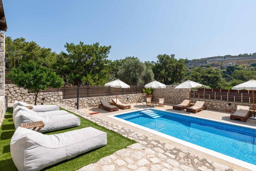 a pool with chaise lounge chairs and a swimming pool at Adonis Villa in nature in Ixia
