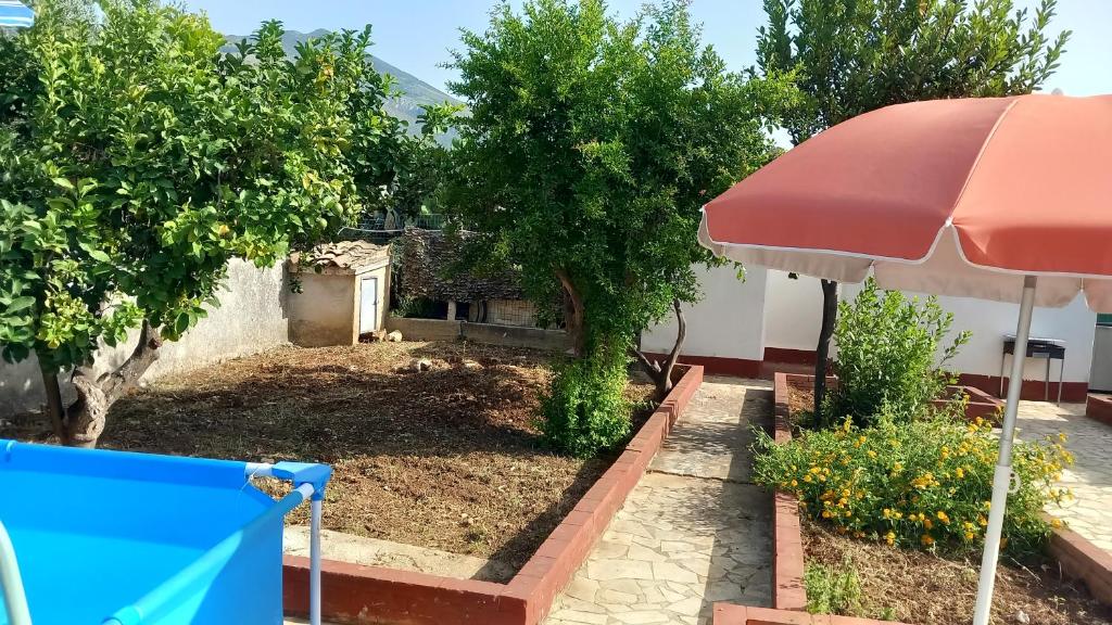 a yard with trees and a red umbrella at Villa Rosa in Castellammare del Golfo