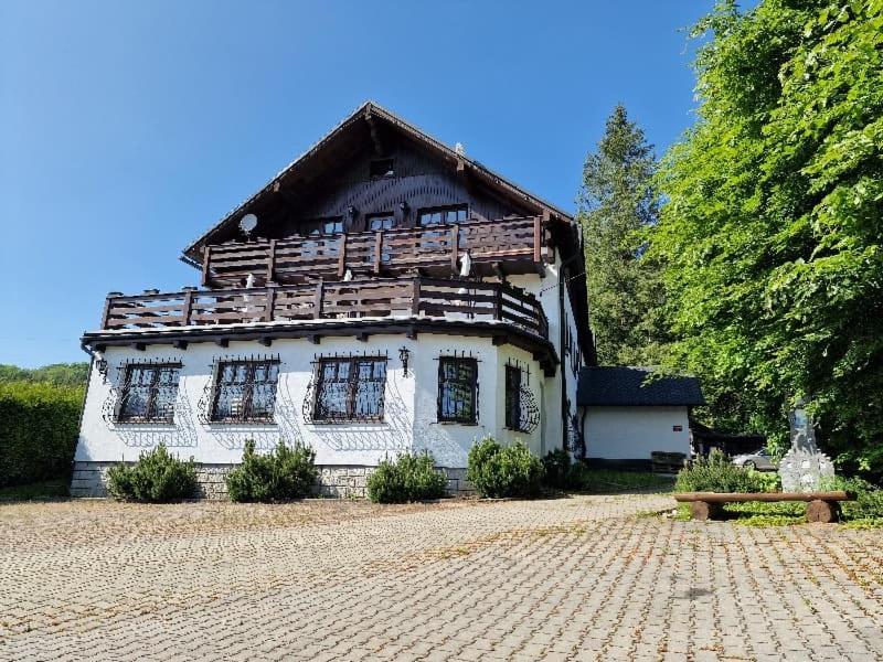 een groot wit huis met een houten dak bij Apartmány Slezský Dům in Jeseník