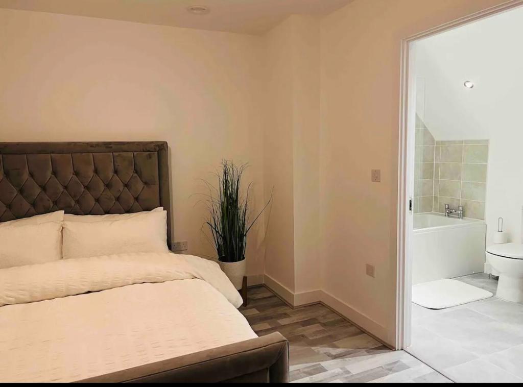 a bedroom with a bed and a tub and a sink at Luxurious new built kingsize bedroom in Manchester