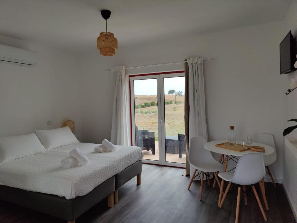 Schlafzimmer mit einem Bett, einem Tisch und einem Fenster in der Unterkunft Monte da Isabel in Vale de Água