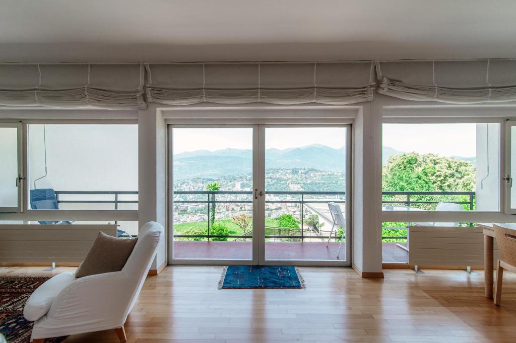 sala de estar con sofá blanco y ventanas grandes en Aldesago City View by Quokka 360 - flat with a breathtaking view, en Viganello