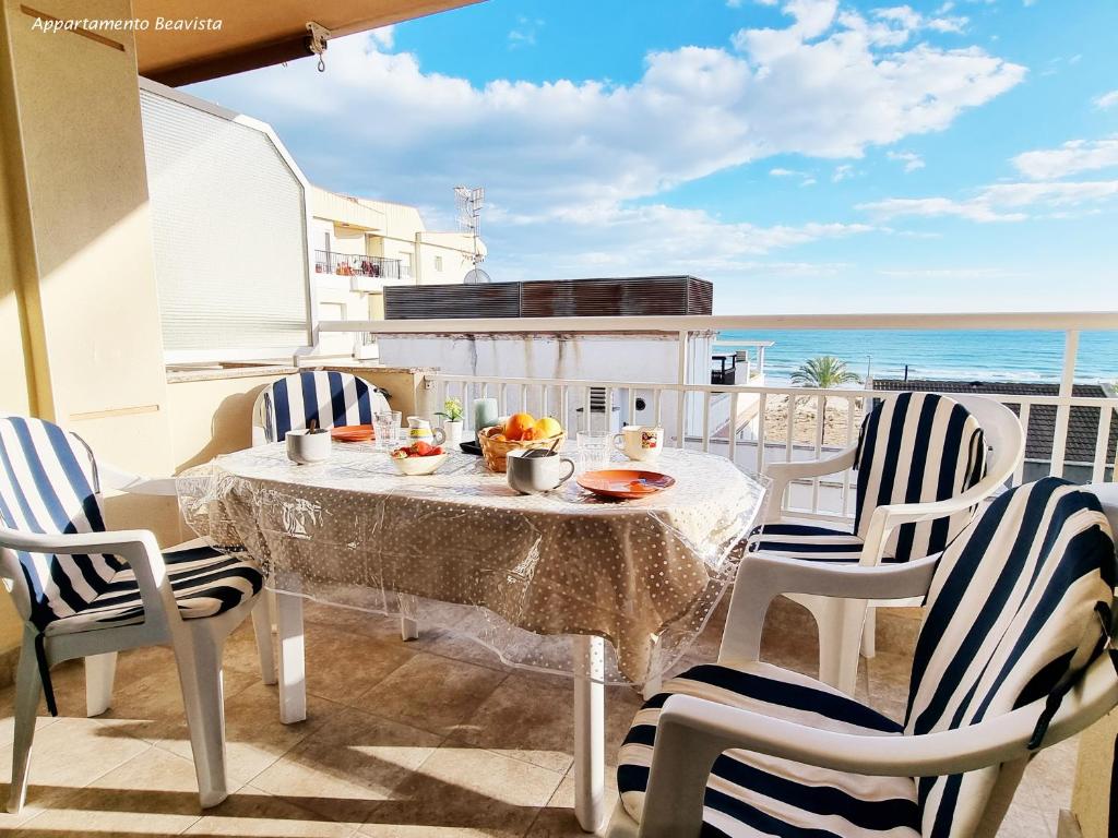 uma mesa e cadeiras numa varanda com praia em Sublime sea view apartement em Calafell