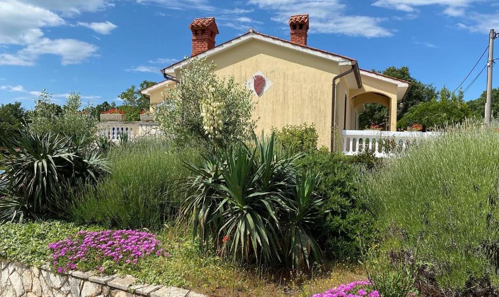 a house in the middle of a garden with flowers at Villa Yucca Istra in Labin