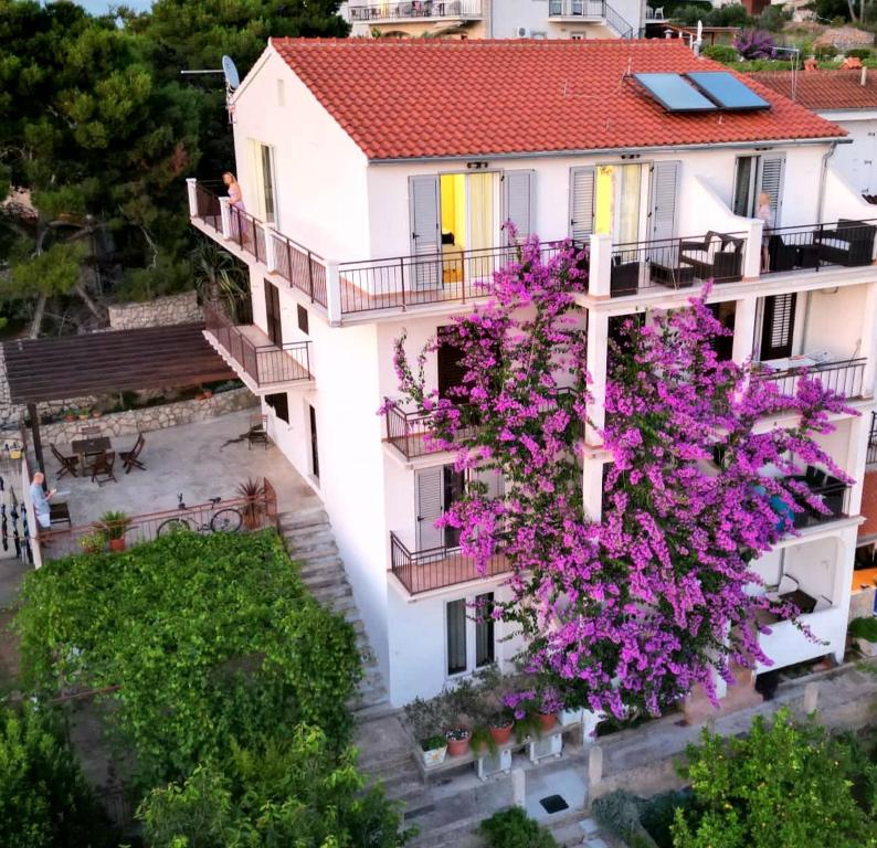 un edificio de apartamentos con flores púrpuras en los balcones en Apartmani Mladina, en Jelsa