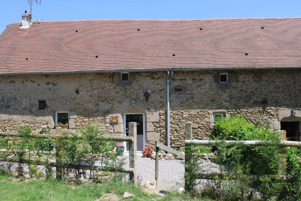 una antigua casa de piedra con techo rojo en Petite Ferme Embir, 