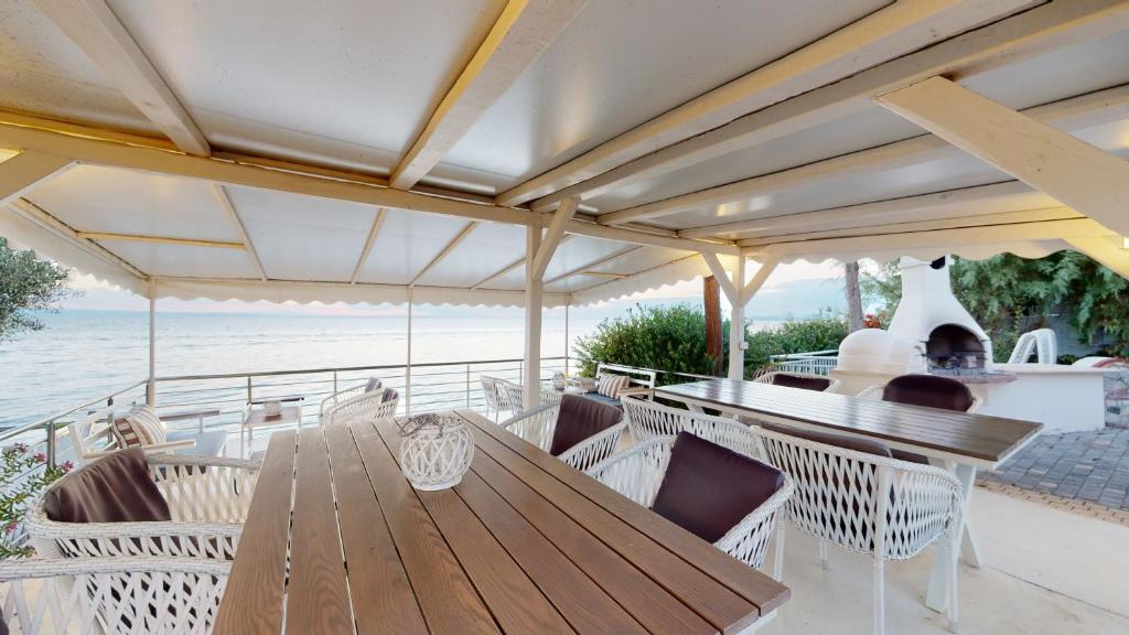 a wooden table and chairs on a patio with the ocean at Acrotel Athena Villa in Elia