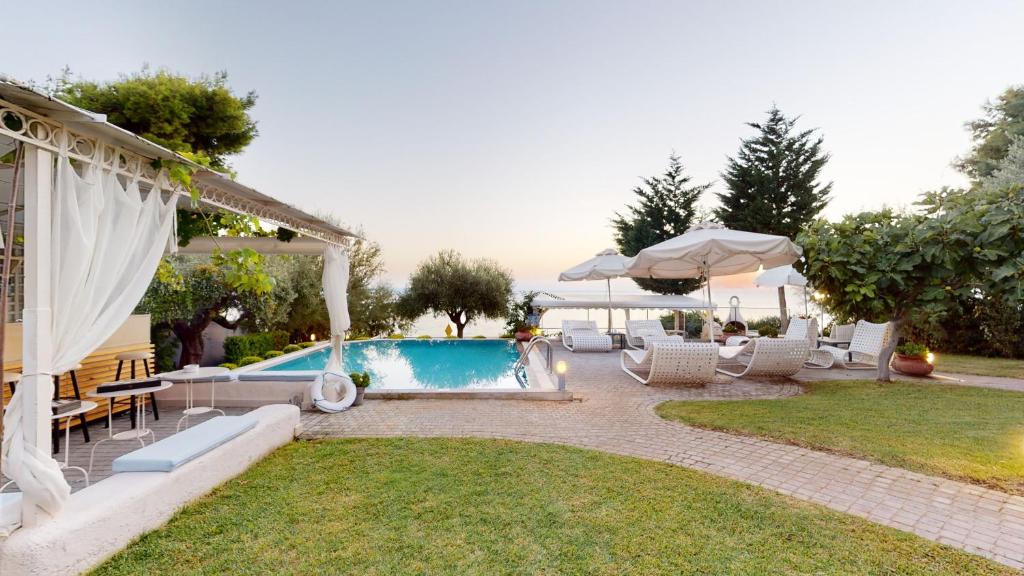 a backyard with a pool and chairs and an umbrella at Acrotel Athena Villa in Elia