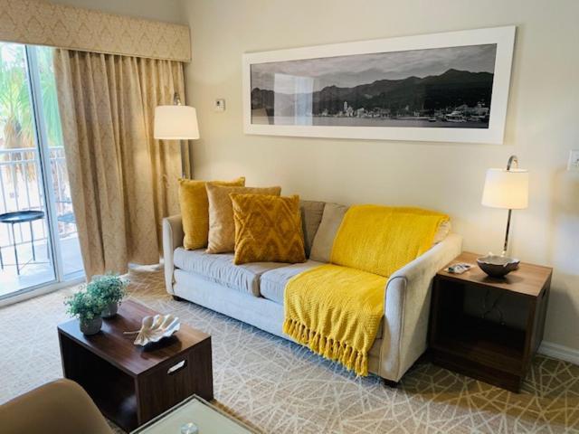 uma sala de estar com um sofá com um cobertor amarelo em Amazing 1 Bedroom Resort 2 miles from Universal em Orlando