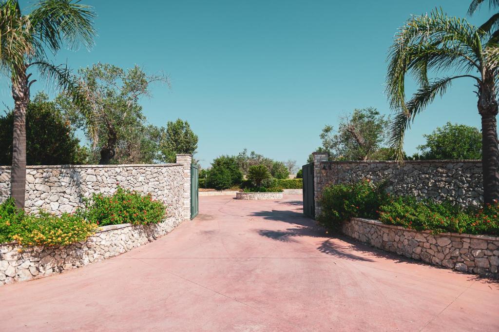 a pathway with a stone wall and palm trees at Villa Maria in Sanarica