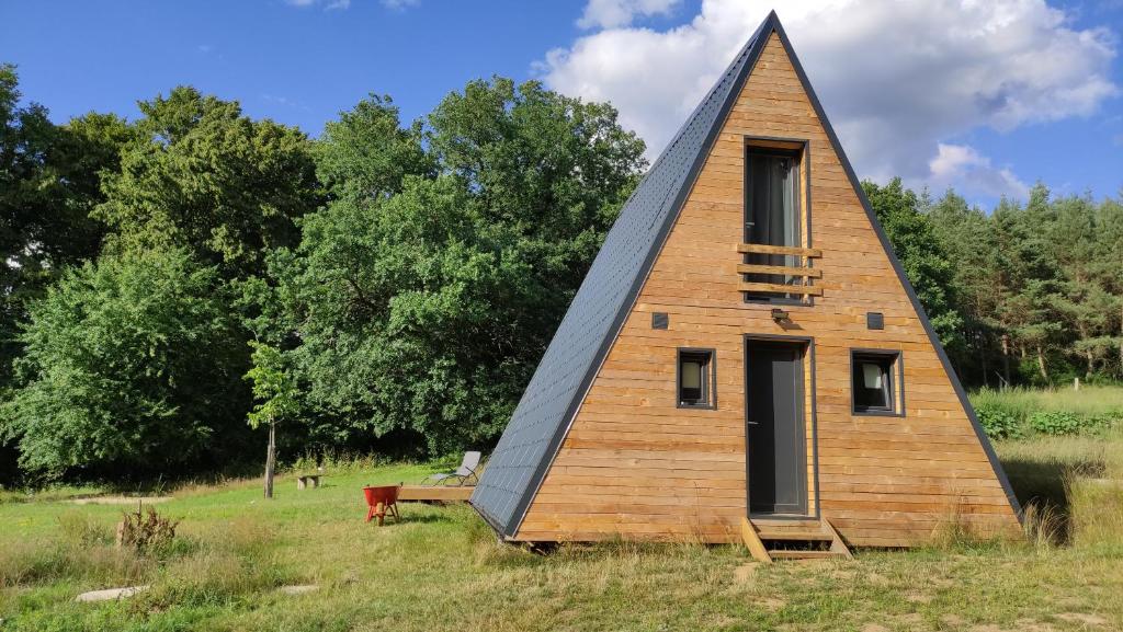 una casa con un techo triangular en un campo en La maison en A, en Meix-devant-Virton