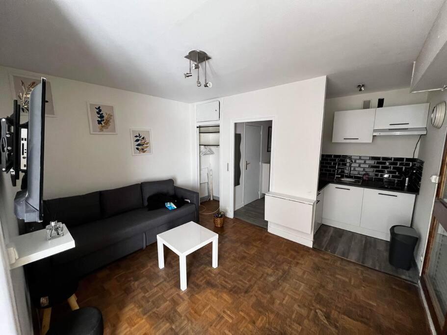 sala de estar con sofá negro y mesa en Appartement T2 Chalons, en Châlons-en-Champagne