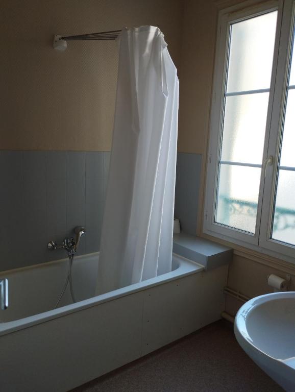 a bathroom with a tub and a shower curtain at Le Nid - Studios in Chartres