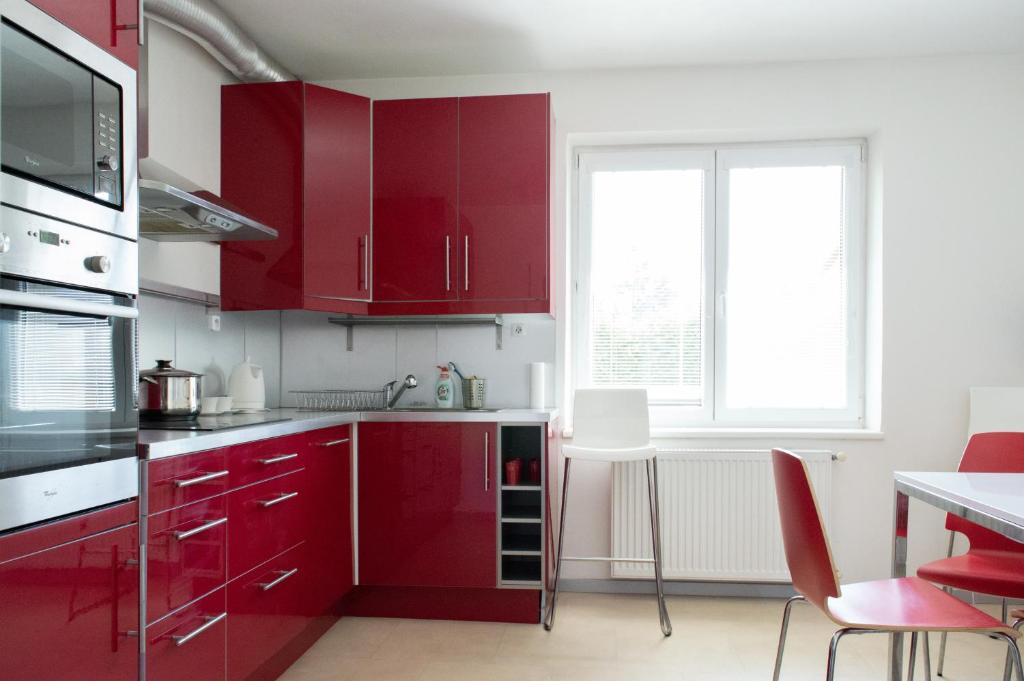 czerwona kuchnia z czerwonymi szafkami i oknem w obiekcie Ubytování Kateřina w mieście Skalná