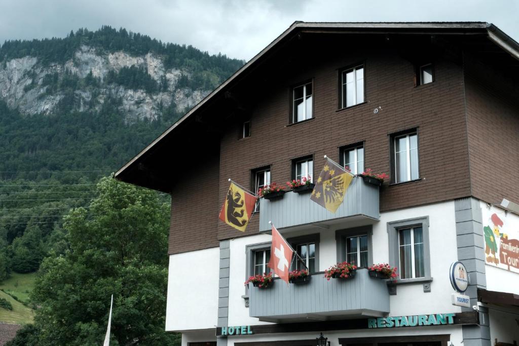 a building with flags on the side of it at Hotel Tourist in Meiringen