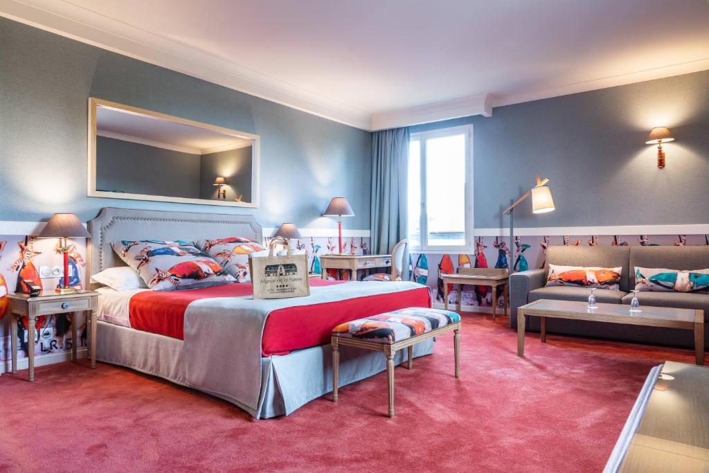 a bedroom with a bed and a couch in a room at Le Manoir De La Poterie & Spa in Cricquebœuf