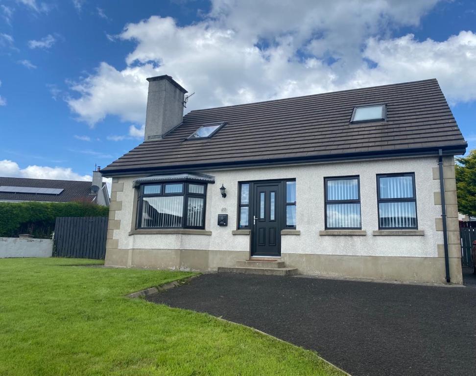 a white house with a black door and a yard at Holiday Home in Ballycastle - Fáinne na Cairde in Ballycastle