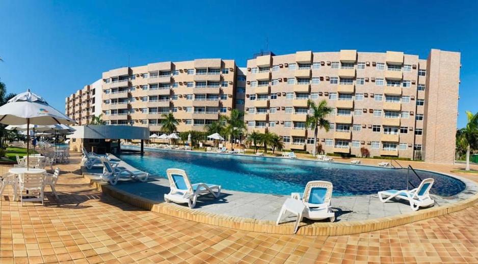 a swimming pool with lounge chairs and a large building at Flat Gran Lençóis in Barreirinhas