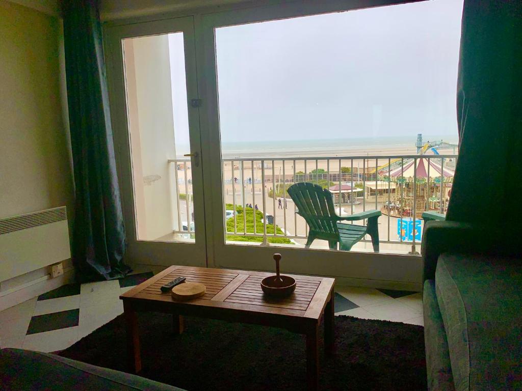 un salon avec une table et une grande fenêtre dans l'établissement Arcadia appart face mer 7 pers, à Le Touquet-Paris-Plage