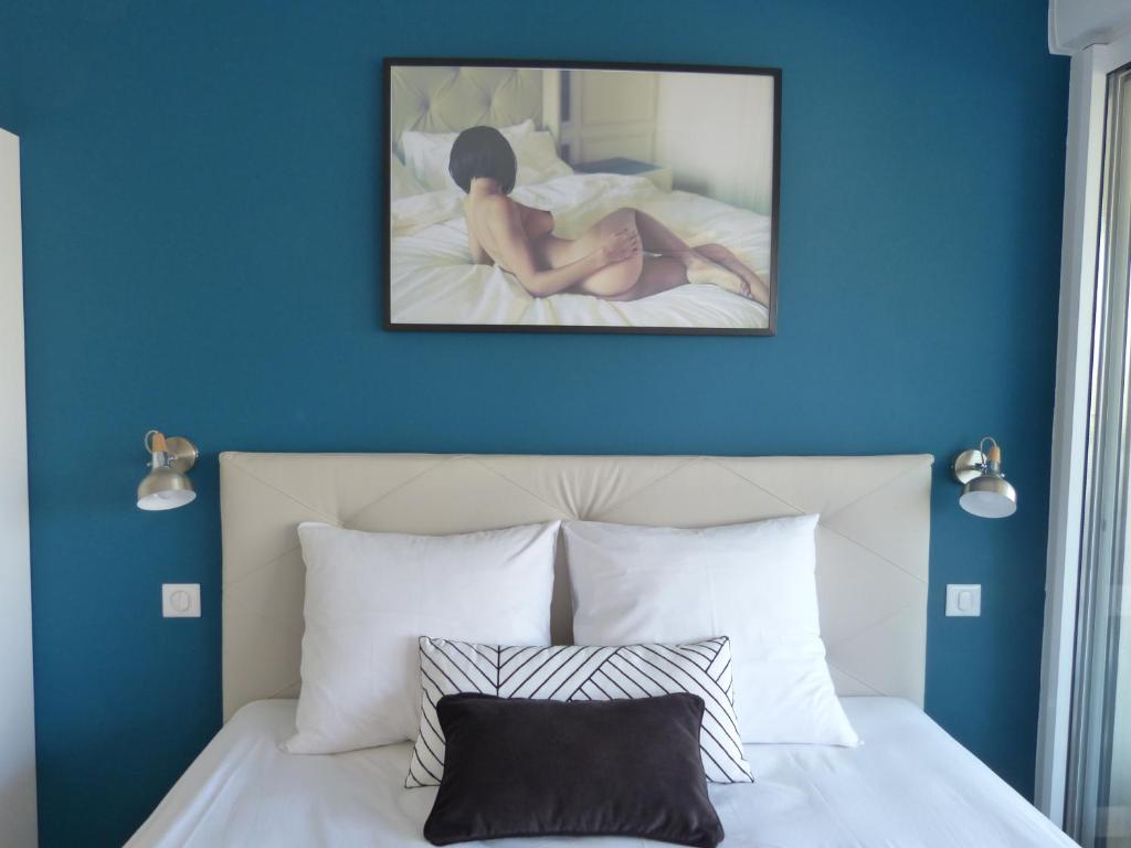 une femme assise sur un lit avec un mur bleu dans l'établissement Studio Blue Marina Luxe - Port Nature - Village Naturiste, au Cap d'Agde
