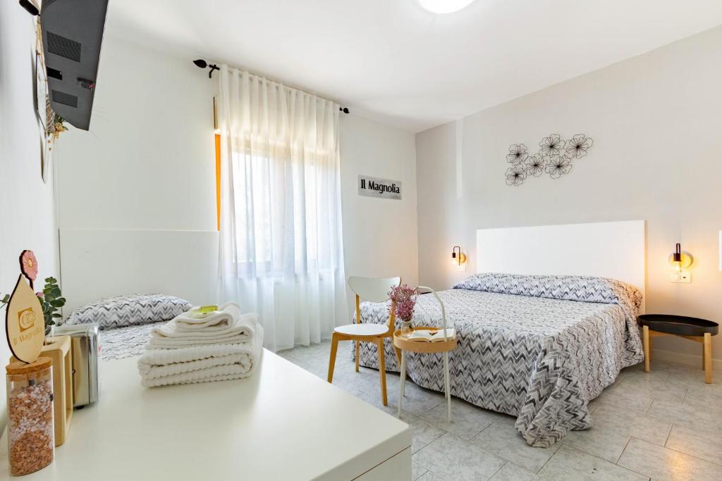 a white bedroom with two beds and a table at Il Magnolia in Francavilla al Mare