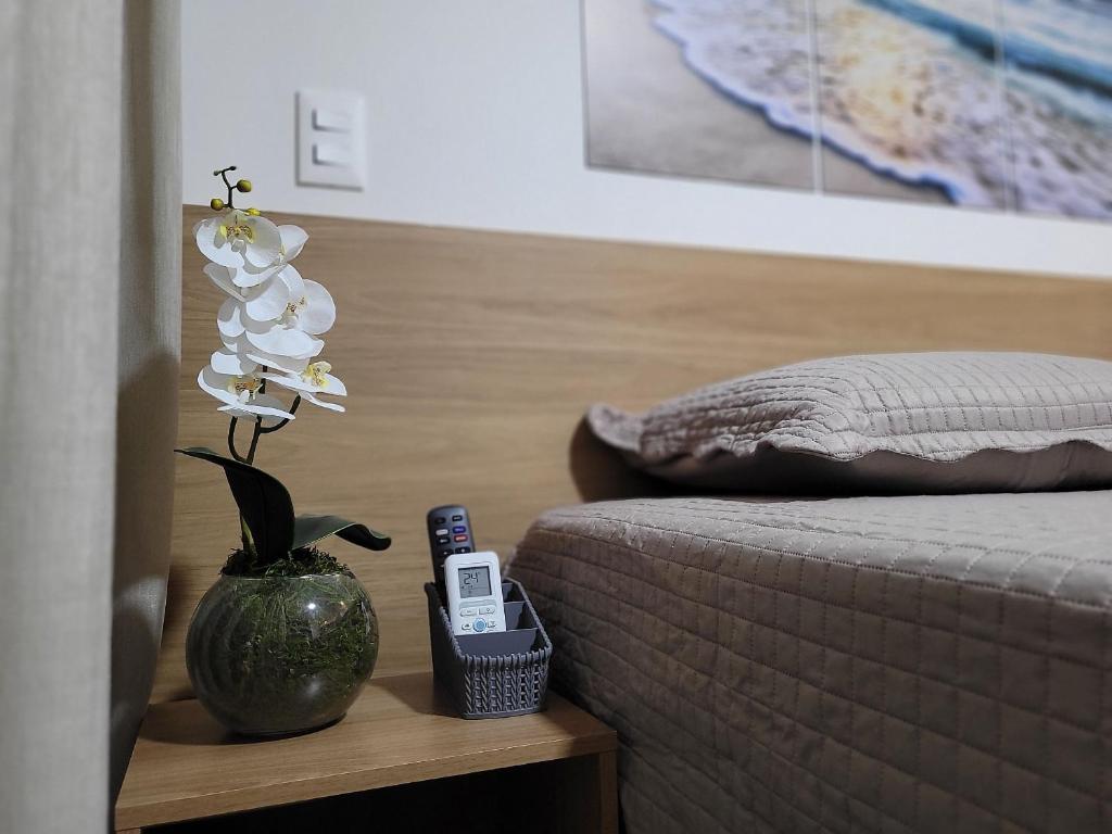 a bedroom with a bed and a vase with flowers on a table at Flats na praia do Bessa in João Pessoa
