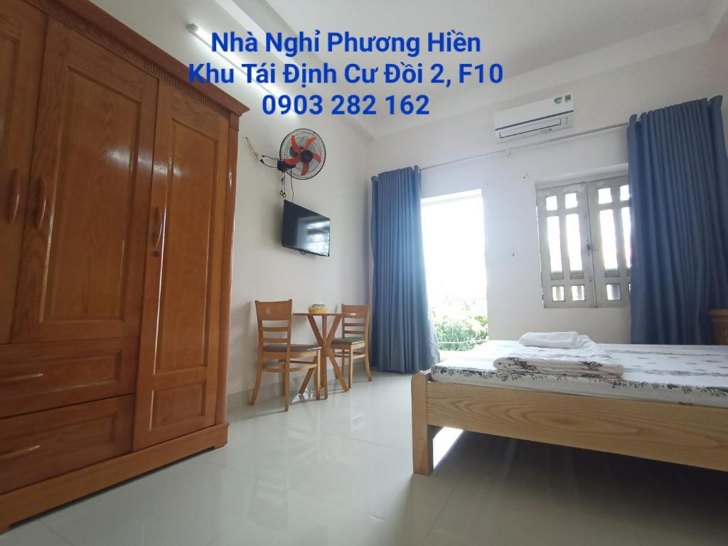 1 dormitorio con 1 cama, mesa y sillas en Nhà nghỉ PHƯƠNG HIỀN, en Vung Tau