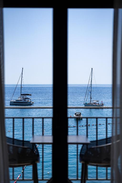 two boats in the ocean viewed from a window at Hotel California by Aycon in Sveti Stefan