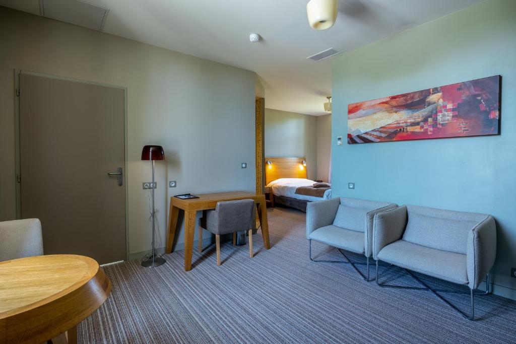 a hotel room with a bed and a table and chairs at Hôtel et SPA du Château in Lagord