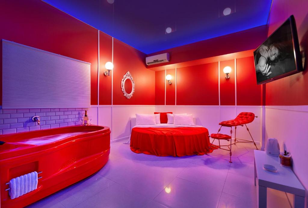 a room with a bed and a bathtub and a red room at Metro Elegance Suites in Tel Binyamin