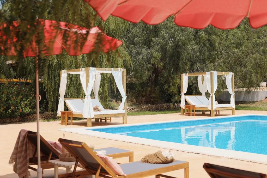 two lounge chairs and a swimming pool with an umbrella at Llucatx Menorca in Son Parc