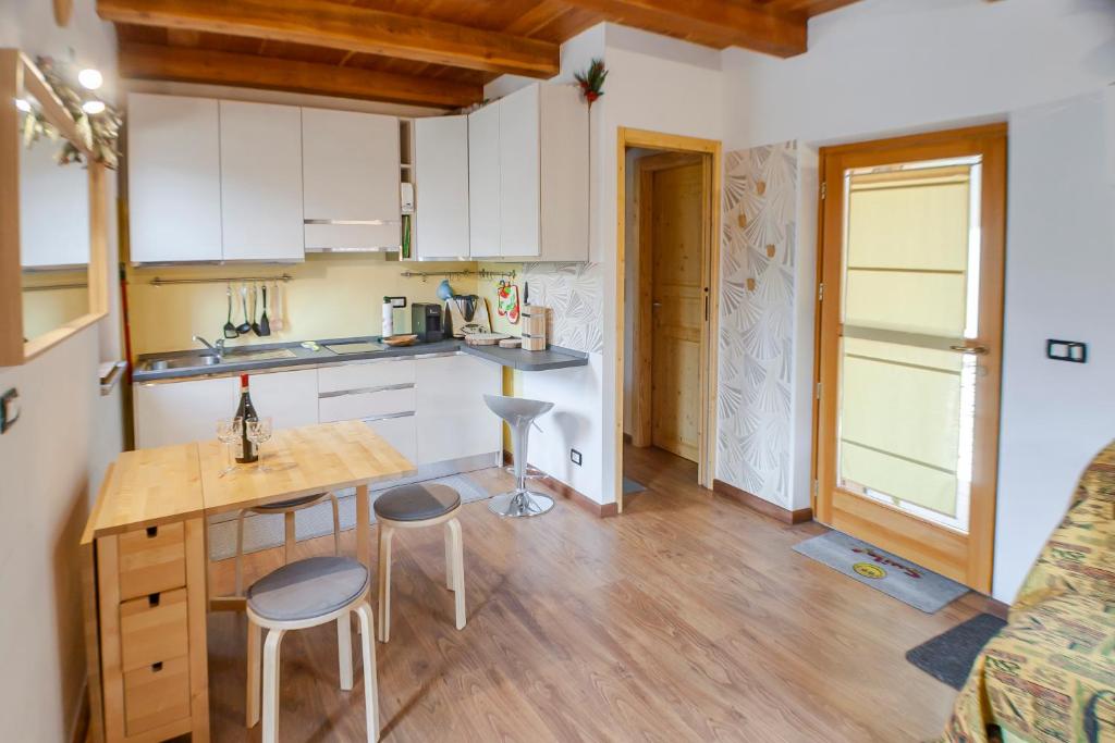 a kitchen with white cabinets and a table and stools at Allo Villo Lovely Apartment in Ostana