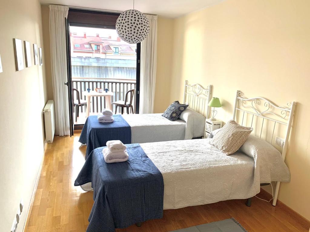 a bedroom with two beds and a couch and a window at Apto La Manzanina con Parking in Villaviciosa