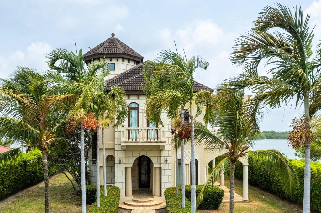 a house with palm trees in front of it at Villa Castello- Water Views & Resort Amenities in Placencia