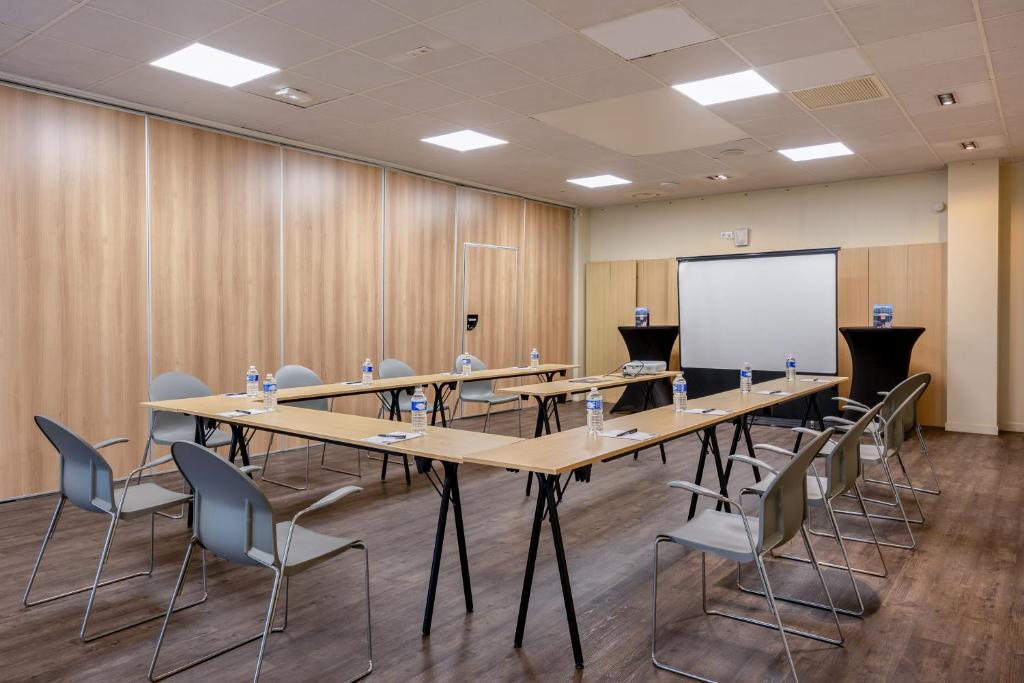 a conference room with tables and chairs and a whiteboard at Hôtel et SPA du Château in Lagord