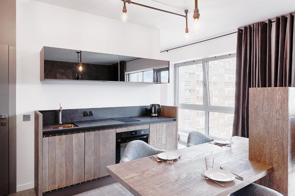 cocina y comedor con mesa de madera en Domaniewska Qbik Lofts, en Varsovia