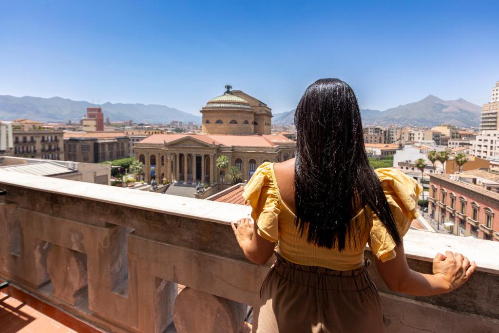 Eine Frau, die auf einem Felsvorsprung steht und eine Stadt ansieht. in der Unterkunft Le Gemme di Cavour Luxury Rooms in Palermo