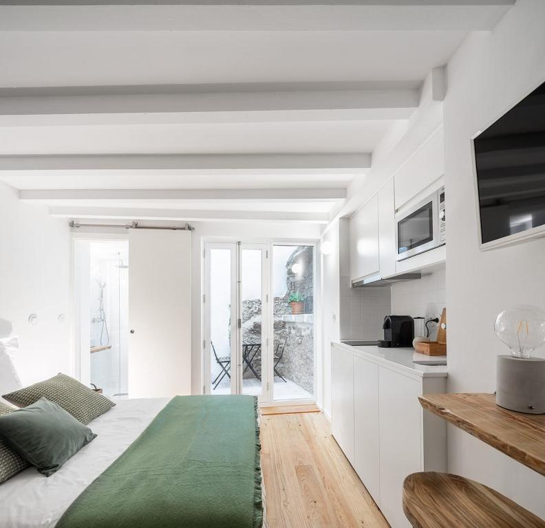 a white room with a bed and a kitchen at Loureiro 59 in Coimbra