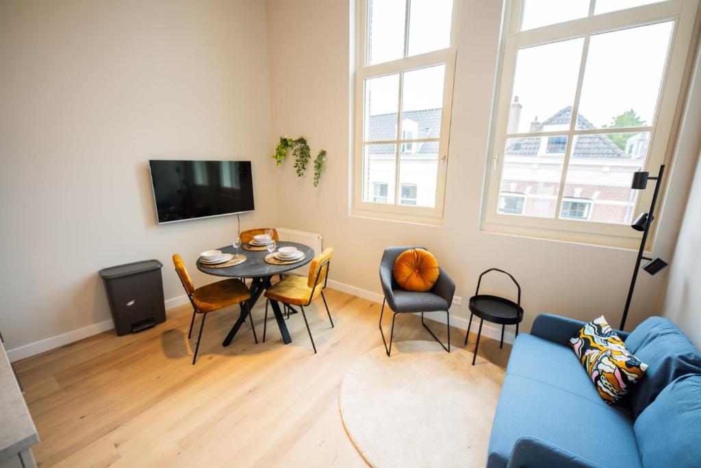 een woonkamer met een blauwe bank en een tafel en stoelen bij Breathtaking 3 Bedroom Apartment in Rotterdam