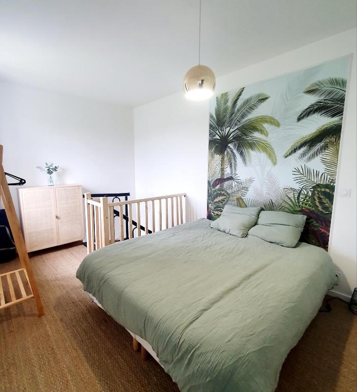 um quarto com uma cama grande e um mural de palmeiras em Maison d'hôtes entre Gap et Sisteron em Lazer