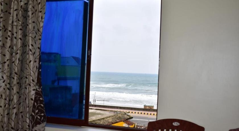 a window with a view of the ocean and the beach at Hotel Lovely Palace ! Puri in Puri