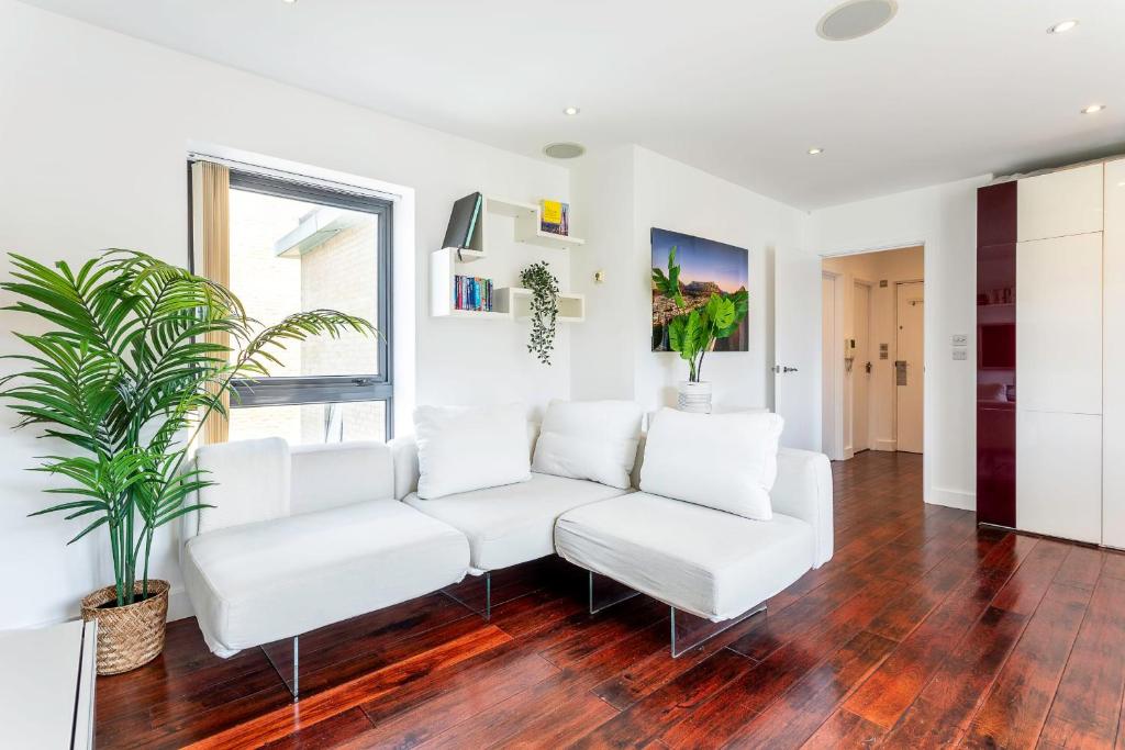 una sala de estar con sofás blancos y una planta en Modern Tower Hill Penthouse en Londres