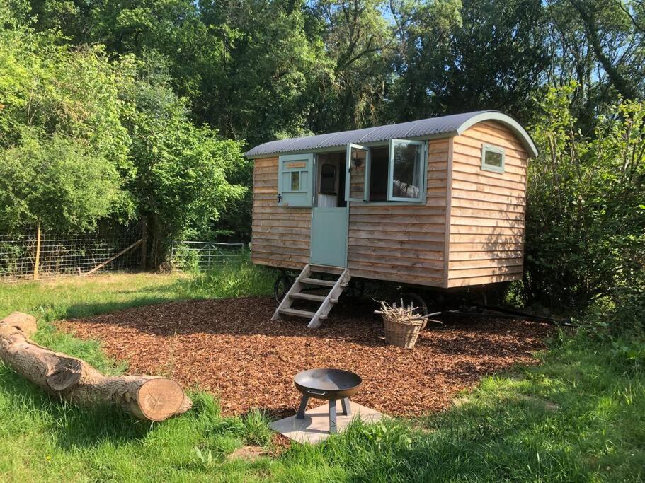 una casita de madera en un patio con un taburete en The Shepherd’s Hut en Whiteparish