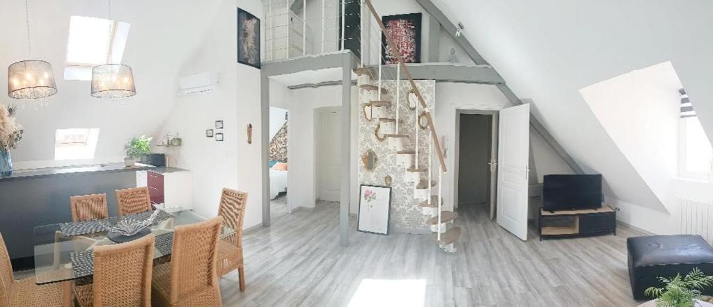 een woonkamer met een trap en een tafel en stoelen bij Au coeur des Remparts in Boulogne-sur-Mer