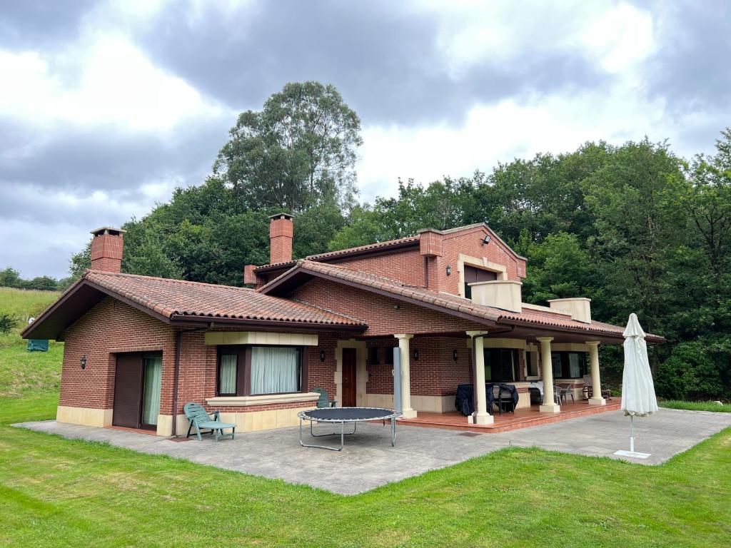 a large brick house with a picnic table and an umbrella at BAKIO BIDEA BOUTIQUE in Mungia