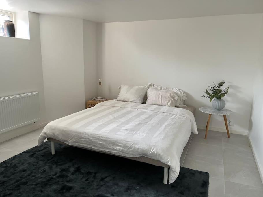a white bedroom with a large bed and a table at Boende nära centrum och natur in Gothenburg