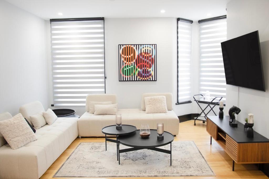 een woonkamer met een witte bank en een tv bij Eat, Explore & Enjoy Downtown Montreal at this Sleek City Escape located in Plateau Mont-Royal - Apt 4 in Montreal