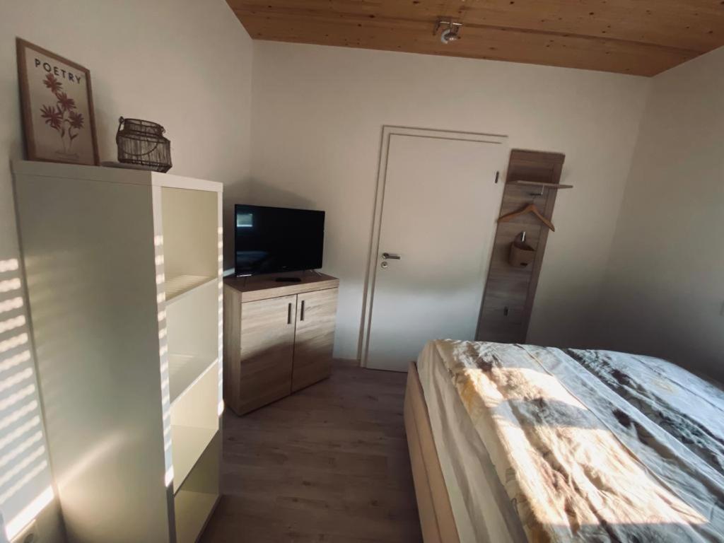 a bedroom with a bed and a tv and a refrigerator at Zimmer m. eigenem Bad und Badewanne direkt am Wald in Amöneburg
