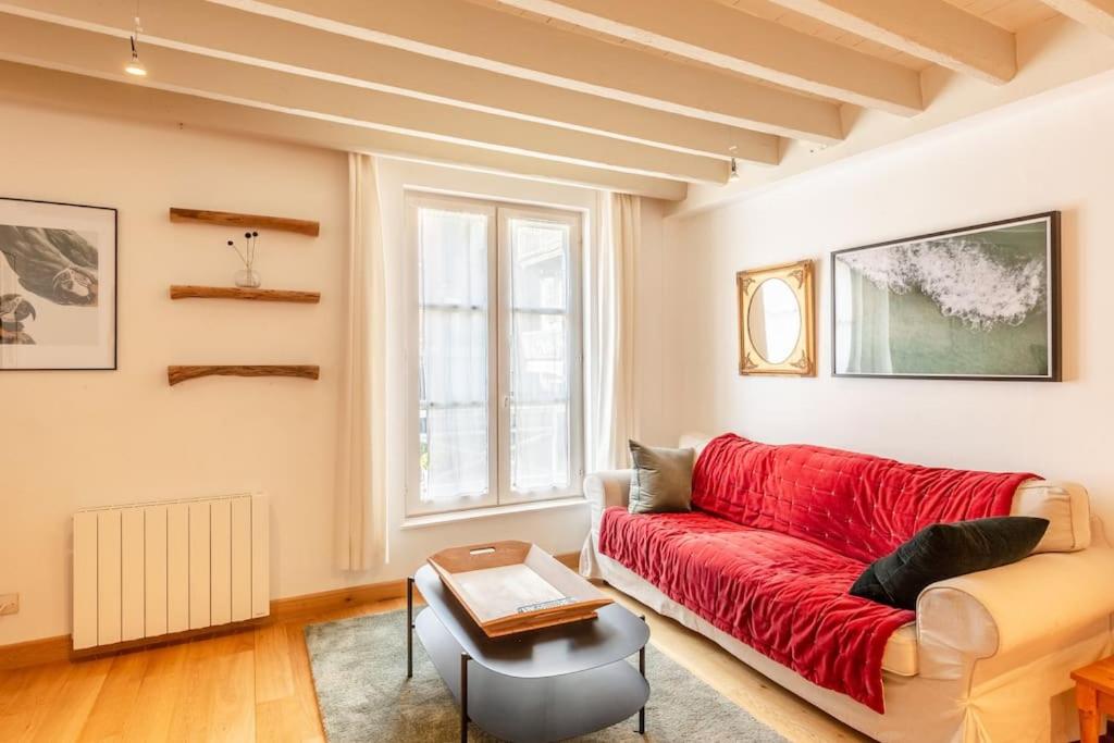 een woonkamer met een rode bank en een raam bij La Belle Place in Honfleur